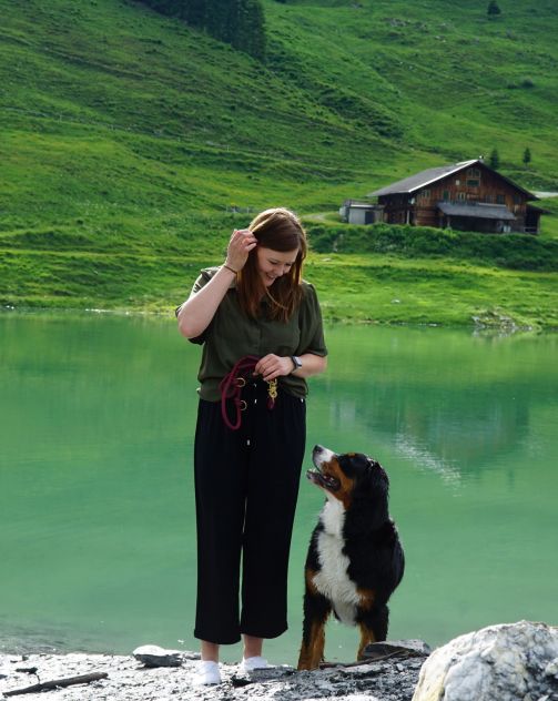 Emma und Lisa stehen vor einem Bergsee und schauen sich an.